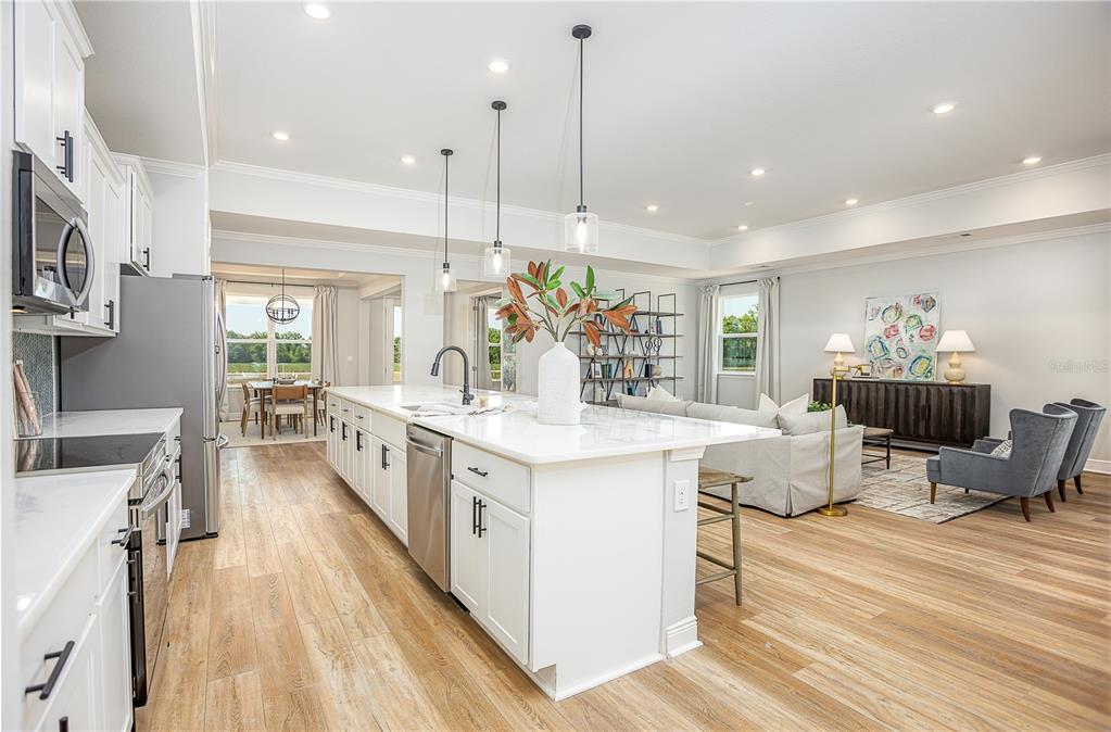A bright, open-concept kitchen and living area featuring a large white island and wood flooring — 52 CACTUS STREET E, HOMOSASSA, FL