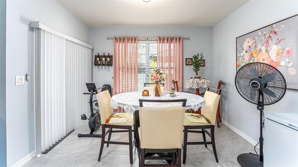 A dining room features a round table with chairs, a stationary bike, and a pedestal fan — 1610 SPRAY TERRACE, ST CLOUD, FL
