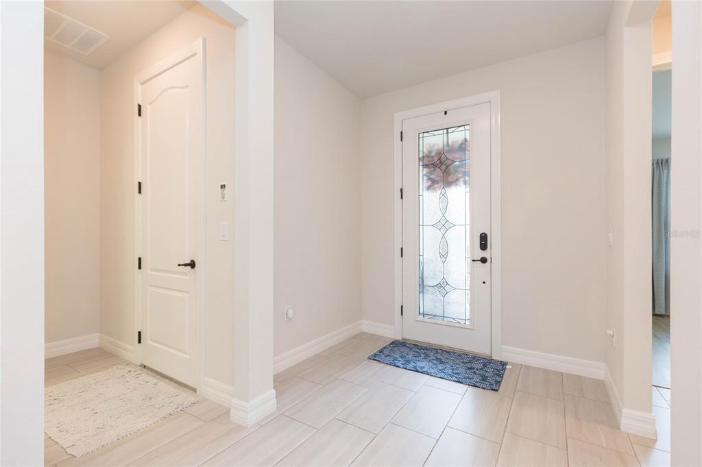 An entryway features light-colored tile flooring, a white front door with glass, and a closet — 7430 POOL COMPASS LOOP, WESLEY CHAPEL, FL