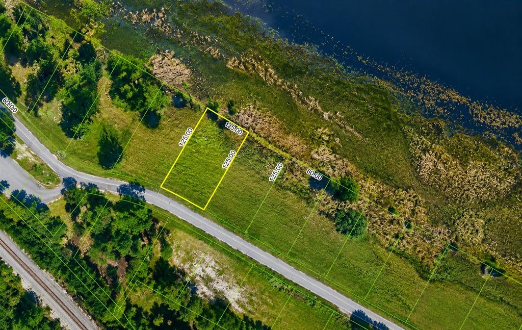 A grassy field leads to a lake under a bright blue sky with white clouds — 998 GRAND LAKE BOULEVARD, AVON PARK, FL