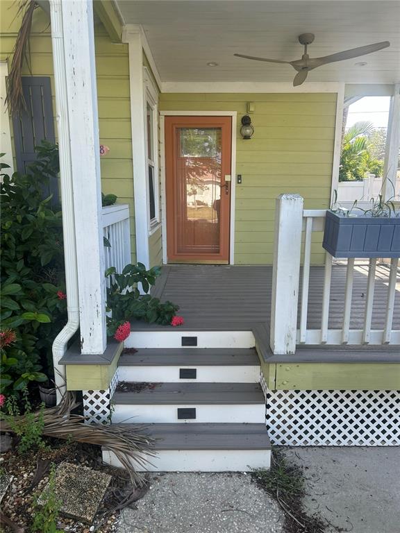 A front porch with gray steps, a light green exterior, and an orange storm door — 3008 DUPONT STREET S, GULFPORT, FL