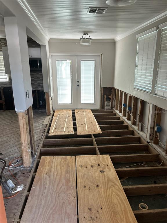 An interior room under renovation features exposed floor joists, plywood subflooring, and open wall studs — 3008 DUPONT STREET S, GULFPORT, FL