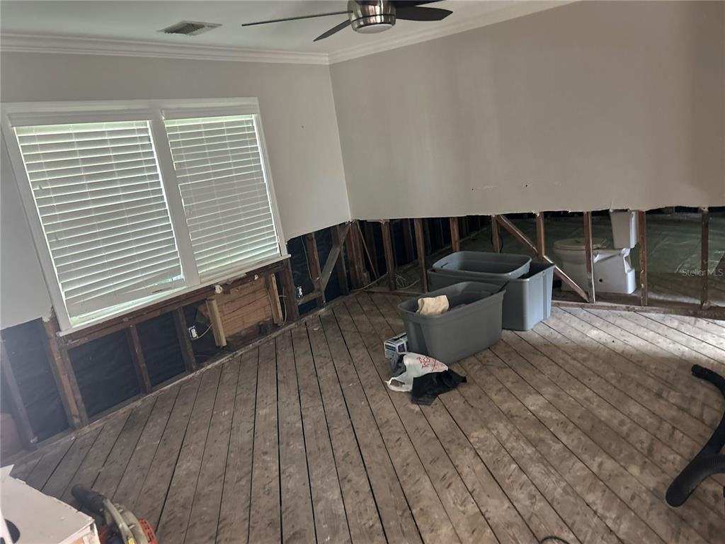 A room under renovation features exposed wall studs, subflooring, and a visible toilet — 3008 DUPONT STREET S, GULFPORT, FL