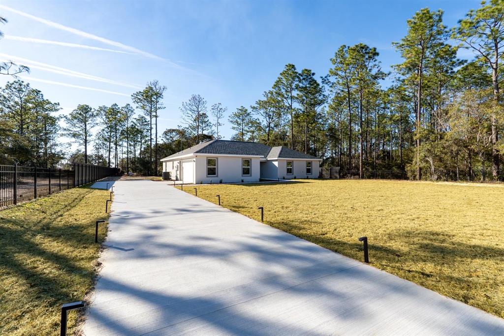 A single-story house with a light-colored exterior, dark roof, and a front lawn — 6920 SW 209TH AVENUE, DUNNELLON, FL