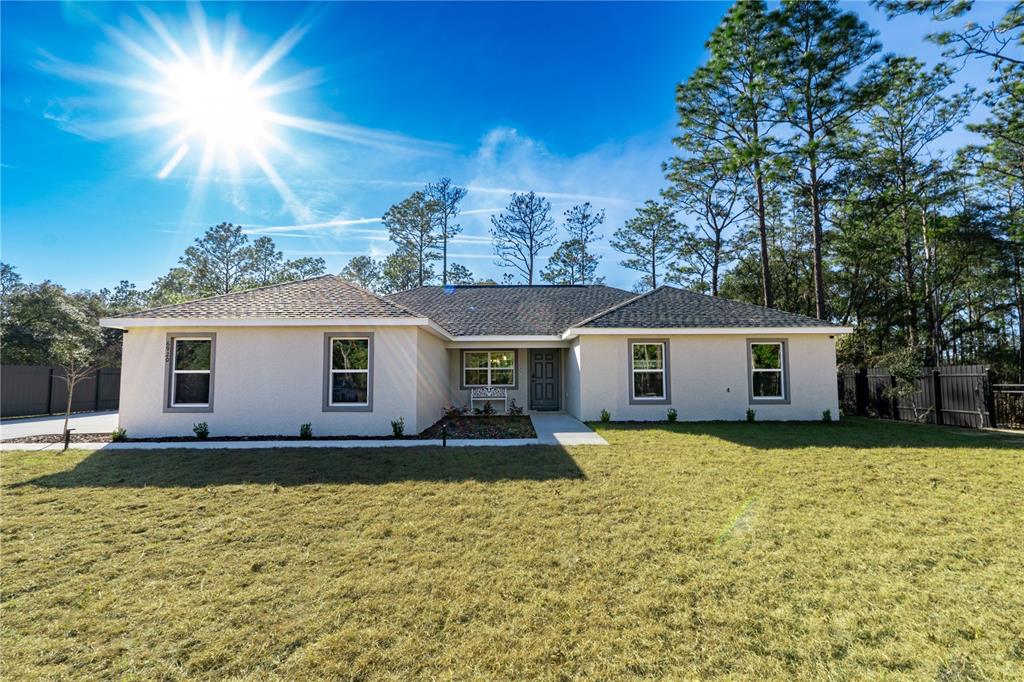 The exterior of a house features a concrete walkway leading to a gray front door — 6920 SW 209TH AVENUE, DUNNELLON, FL