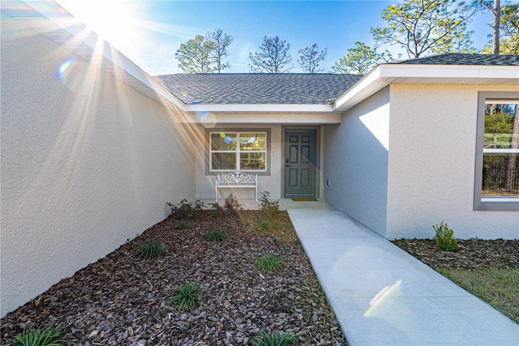 A kitchen features a granite-topped island with bar seating, white cabinets, and stainless steel appliances — 6920 SW 209TH AVENUE, DUNNELLON, FL