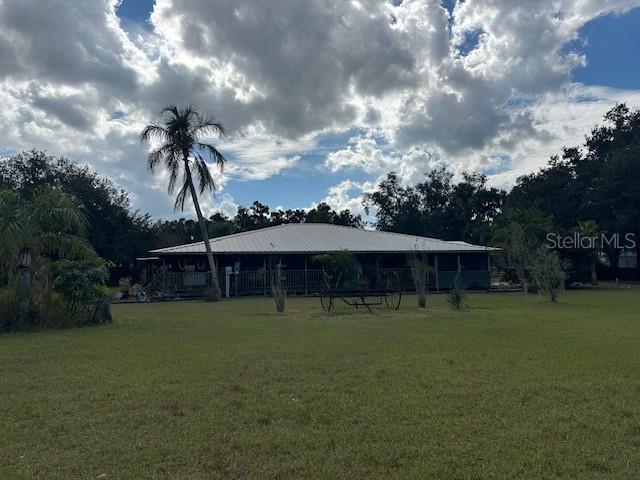 A single-story house with a metal roof and a wrap-around porch sits on a lawn — 10102 LOETSCHER LANE, LITHIA, FL