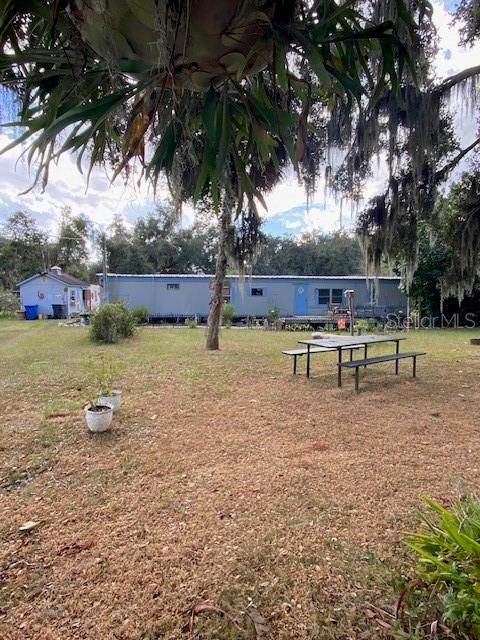 A mobile home sits on a grassy lot with a picnic table in the foreground — 10102 LOETSCHER LANE, LITHIA, FL