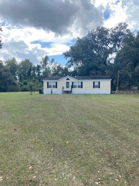 A light-colored manufactured home sits in the center of a large, grassy, tree-lined lot — 10102 LOETSCHER LANE, LITHIA, FL