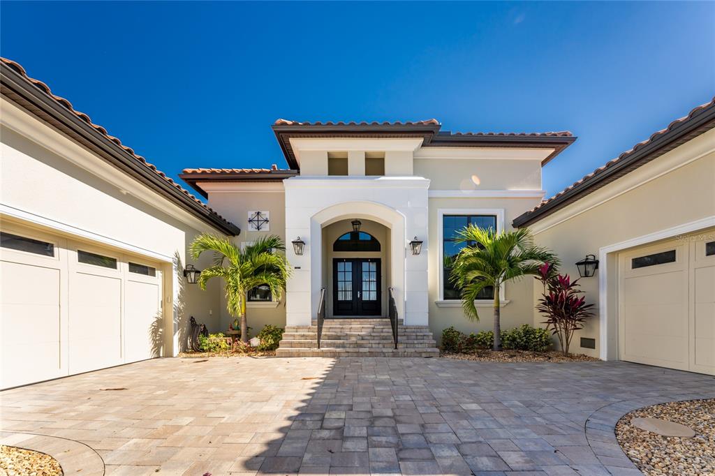 A beige house exterior with a paved driveway, two garages, and a central arched entryway — 265 SEVERIN RD, PORT CHARLOTTE, FL