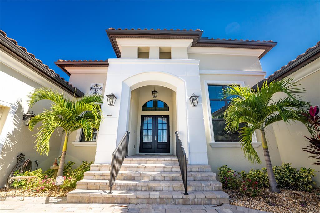 The exterior of a house features a white arched entryway, double doors, and palm trees — 265 SEVERIN RD, PORT CHARLOTTE, FL