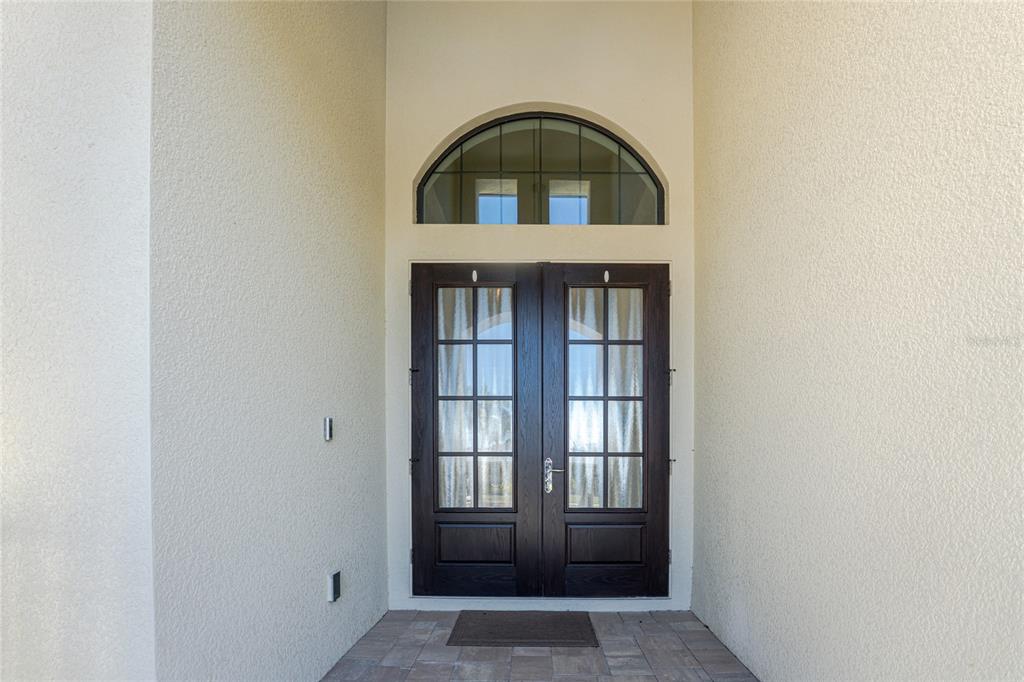 A dark wood double front door with glass panes sits beneath an arched transom window — 265 SEVERIN RD, PORT CHARLOTTE, FL