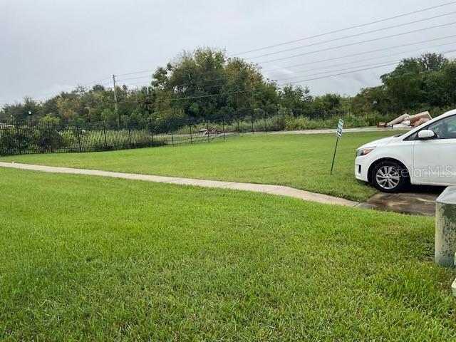 A white car is parked on a grassy lot next to a concrete sidewalk — WILLOW DRIVE, LEESBURG, FL
