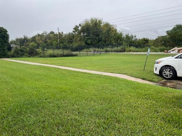 A grassy vacant lot features a concrete sidewalk and a black metal fence — WILLOW DRIVE, LEESBURG, FL