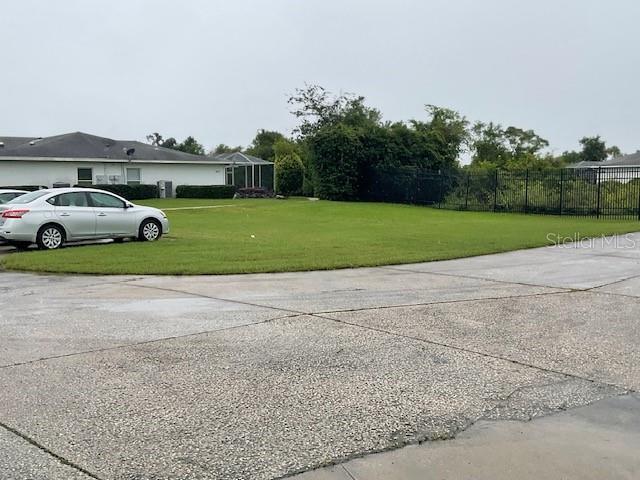 A silver sedan is parked on a grassy lot next to a residential building — WILLOW DRIVE, LEESBURG, FL