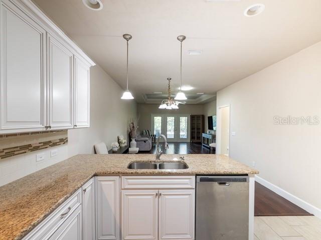 A kitchen features white cabinets, granite countertops, a stainless steel dishwasher, and pendant lighting — 12604 NW 11 PLACE, NEWBERRY, FL