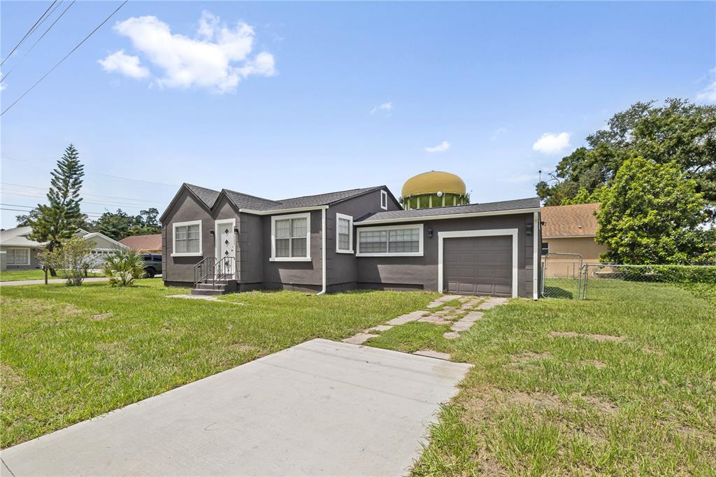 A single-story house with dark gray siding, a front-facing garage, and a yellow water tower — 2202 N GLEN AVENUE, TAMPA, FL