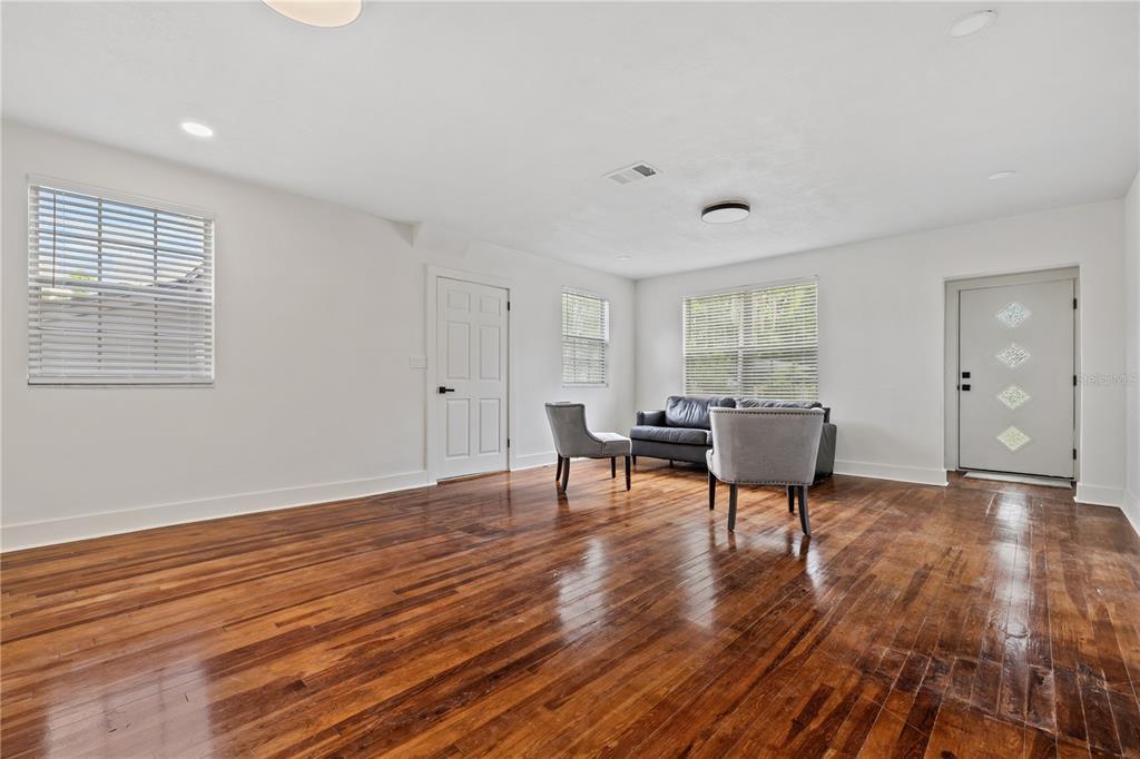 A living room features white walls, dark hardwood floors, two gray chairs, and a sofa — 2202 N GLEN AVENUE, TAMPA, FL