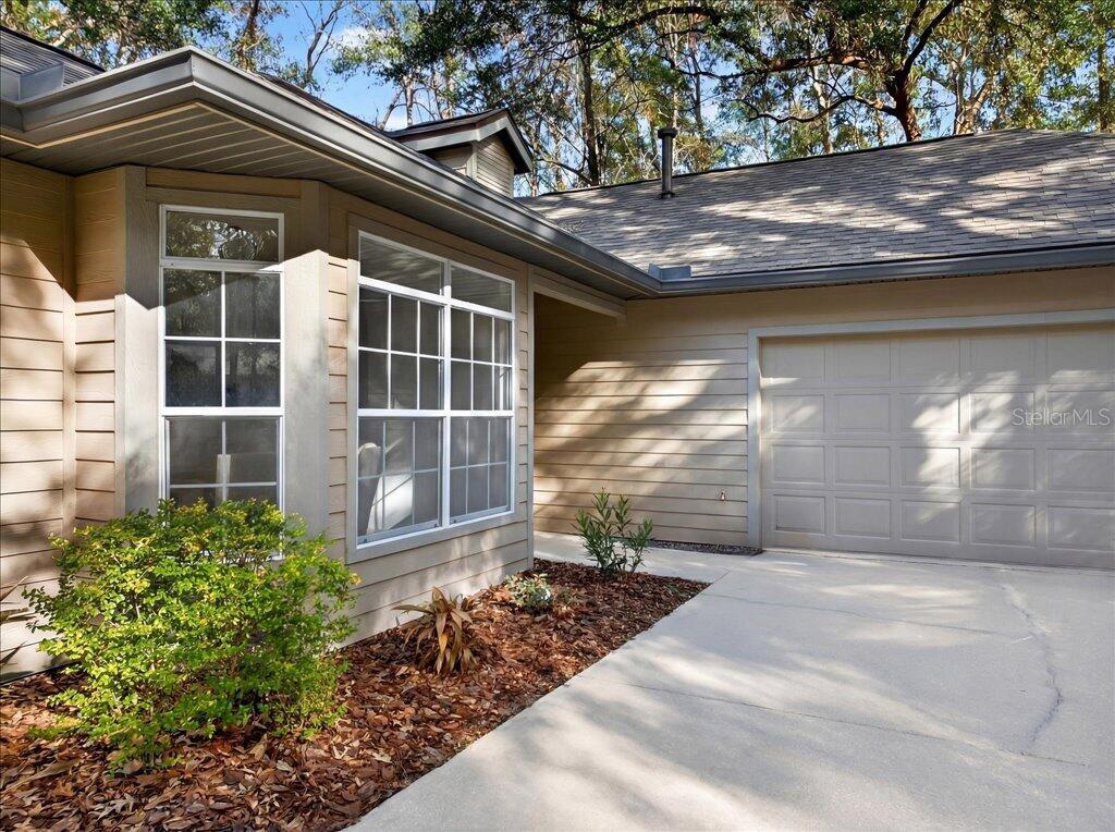 A tan house exterior features a concrete driveway, a garage, and a large bay window — 4412 SW 101ST DRIVE, GAINESVILLE, FL