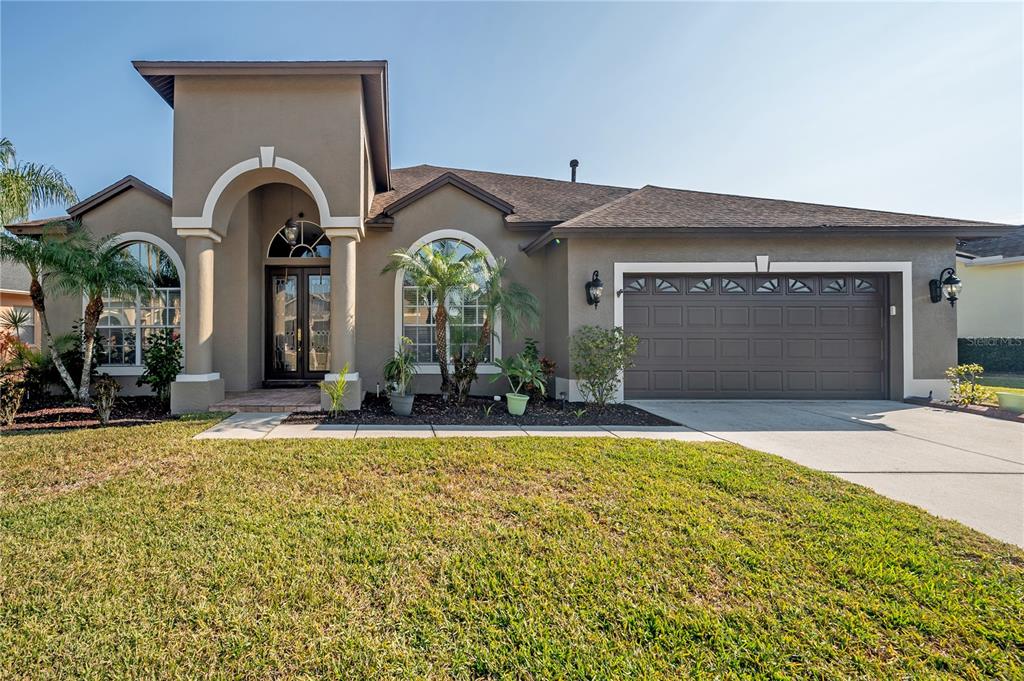 A single-story house with a brown garage, arched windows, and a covered entryway — 10126 LONDONSHIRE LANE, TAMPA, FL
