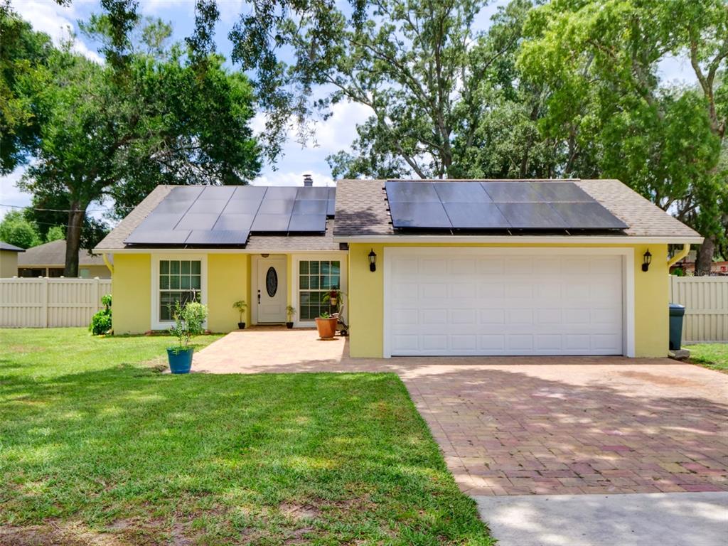 A yellow single-story house with a white garage door and solar panels on the roof — 440 E CITRUS STREET, ALTAMONTE SPRINGS, FL
