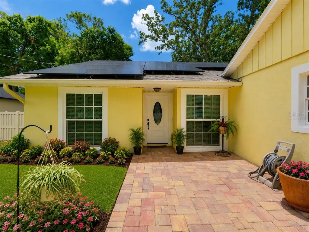 A yellow house exterior features a paved walkway, solar panels, and a front door — 440 E CITRUS STREET, ALTAMONTE SPRINGS, FL