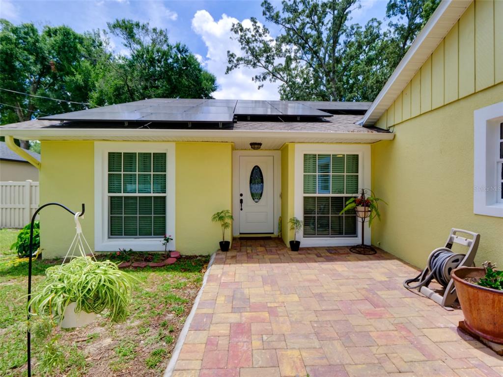A yellow house exterior features a brick paver walkway, white front door, and rooftop solar panels — 440 E CITRUS STREET, ALTAMONTE SPRINGS, FL
