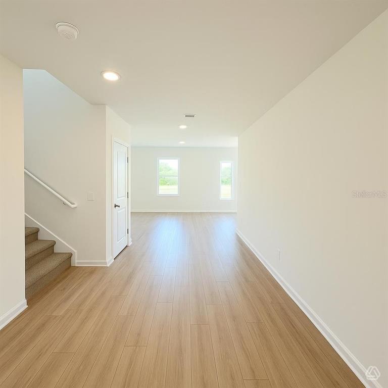 An interior view shows a living area with light wood flooring and a staircase — 12923 RED DEER PLACE, PARRISH, FL