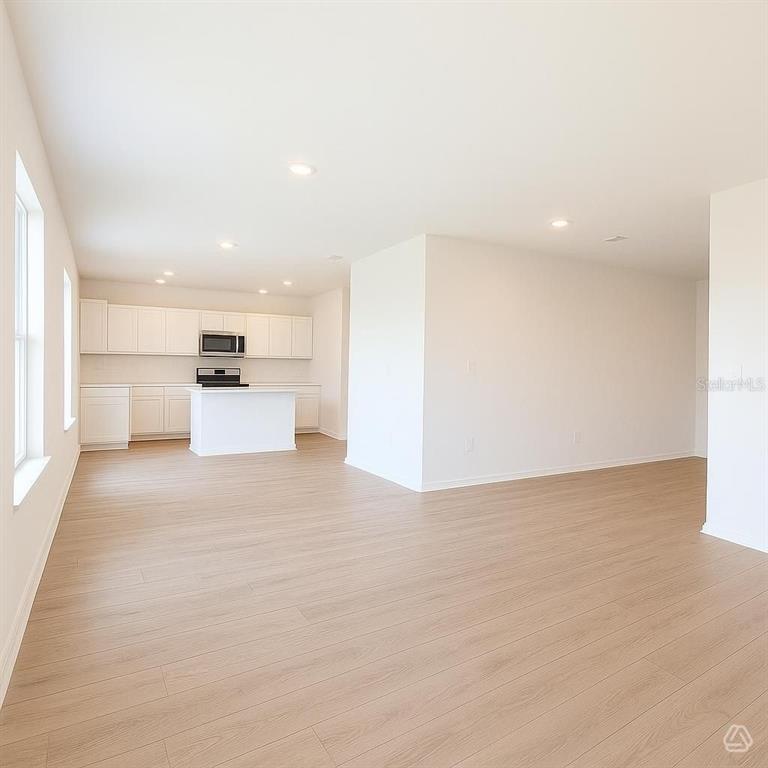 An open-concept kitchen and living area features white cabinetry, a center island, and light flooring — 12923 RED DEER PLACE, PARRISH, FL