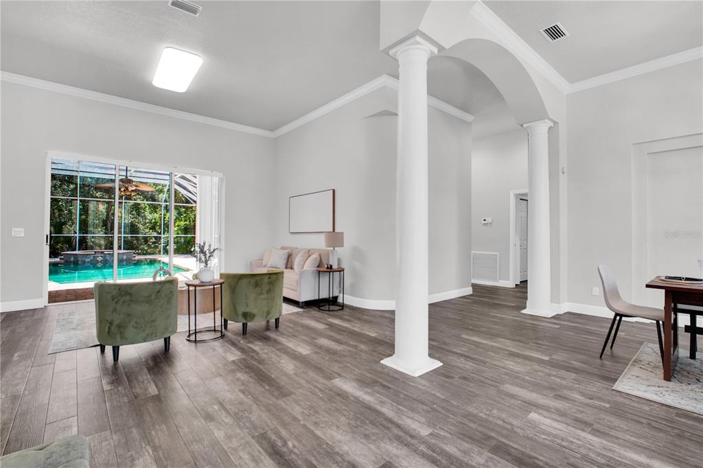 A living area with wood-look flooring, white columns, and a sliding door to a pool — 4931 TURTLE CREEK TRAIL, OLDSMAR, FL