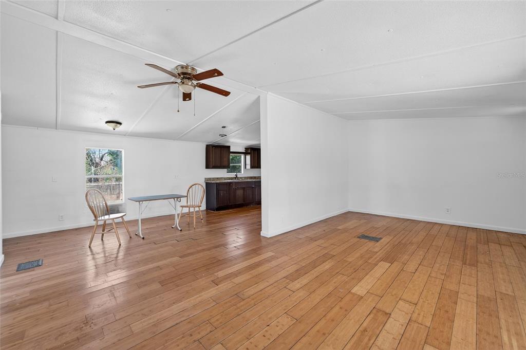 A living area with wood flooring leads into a kitchen with dark wood cabinets — 35238 MANUEL STREET, WEBSTER, FL
