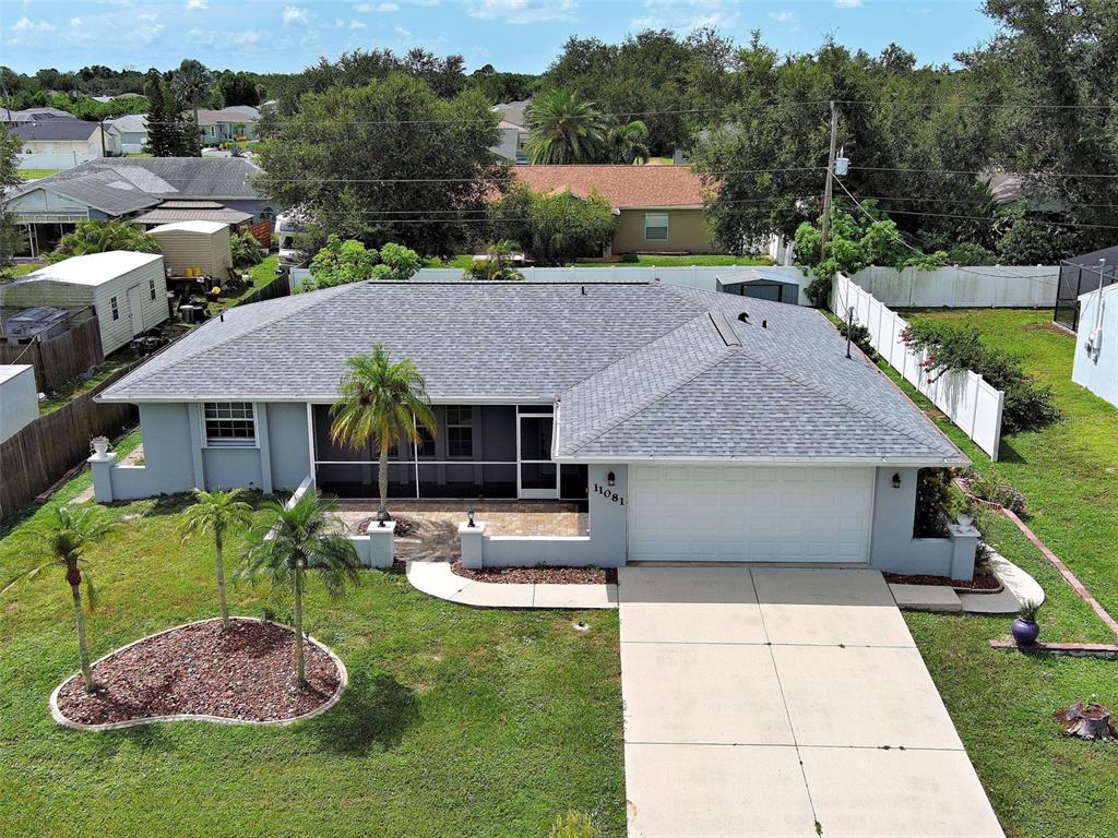 An aerial view of a single-story house with a gray roof, garage, and screened patio — 11081 MAGDALENA AVENUE, ENGLEWOOD, FL