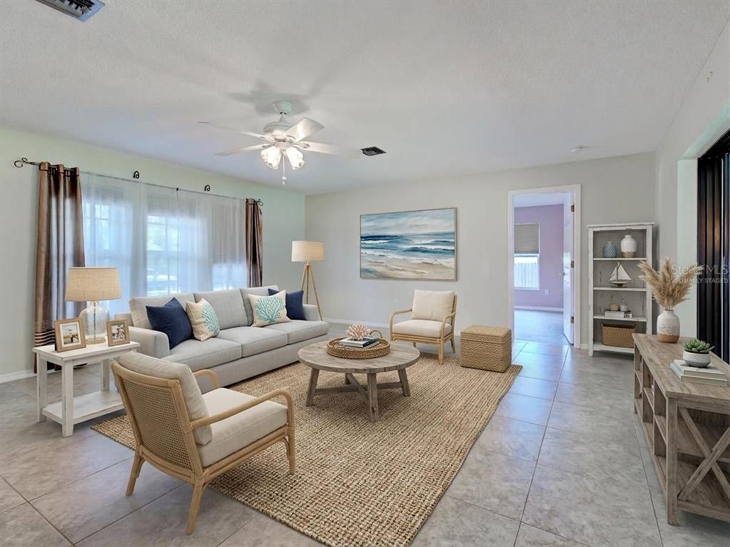 A living room features a light gray sofa, two armchairs, a round coffee table, and tile flooring — 11081 MAGDALENA AVENUE, ENGLEWOOD, FL