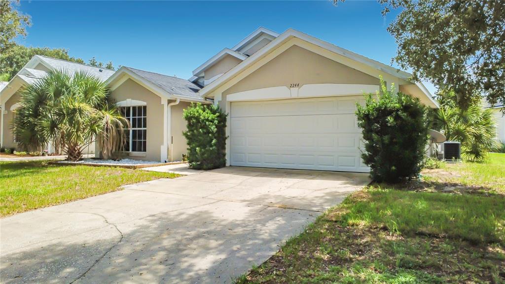 A single-story house with a beige exterior, a two-car garage, and a concrete driveway — 2244 MALLORY CIRCLE, HAINES CITY, FL