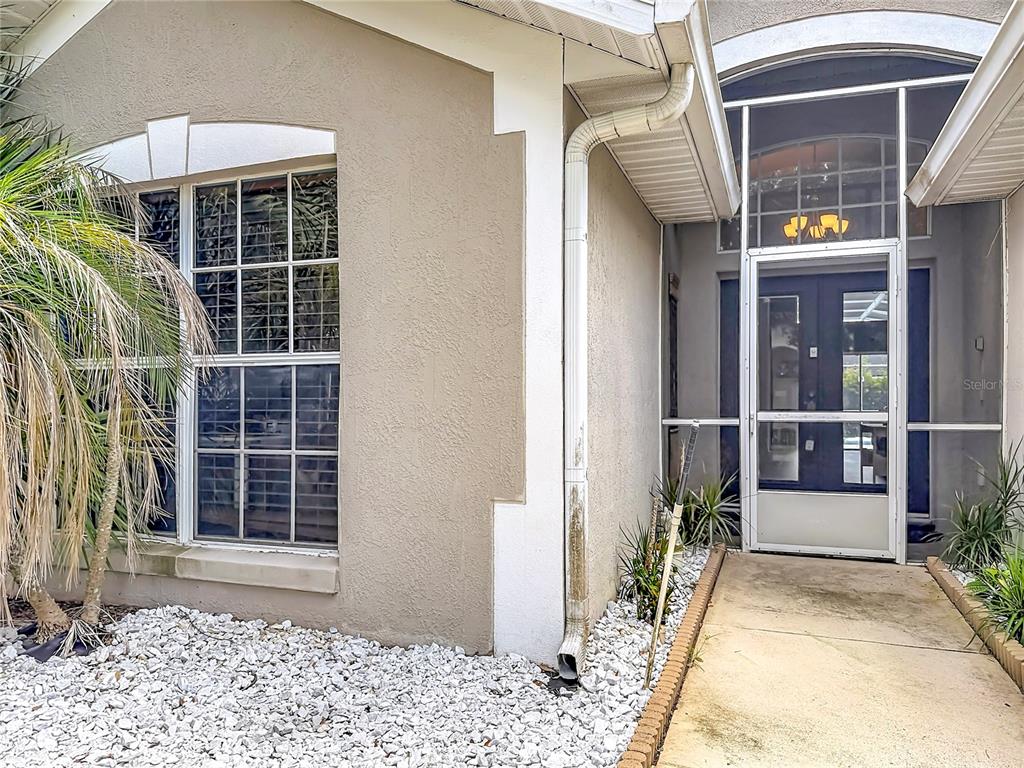 The exterior of a home features a white-framed screen door, a window, and a downspout — 2244 MALLORY CIRCLE, HAINES CITY, FL