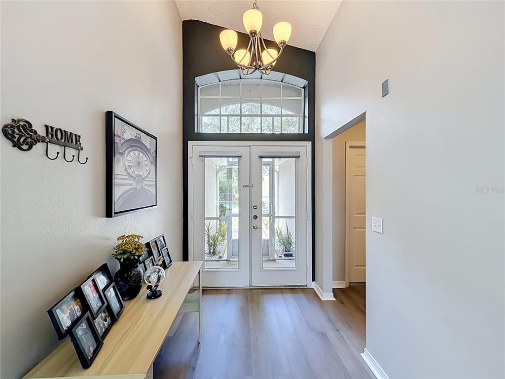 An entryway features a light wood console table, a dark accent wall, and double glass doors — 2244 MALLORY CIRCLE, HAINES CITY, FL