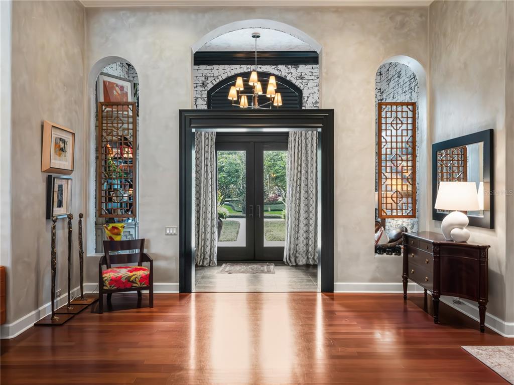 A grand foyer features hardwood floors, arched wall niches, and a dark-framed double door entrance — 16211 VILLARREAL DE AVILA, TAMPA, FL