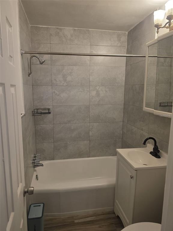 A bathroom features a white bathtub, gray tiled walls, and a small white vanity — 1844 JOHN RIVERS STREET UNIT B, SARASOTA, FL