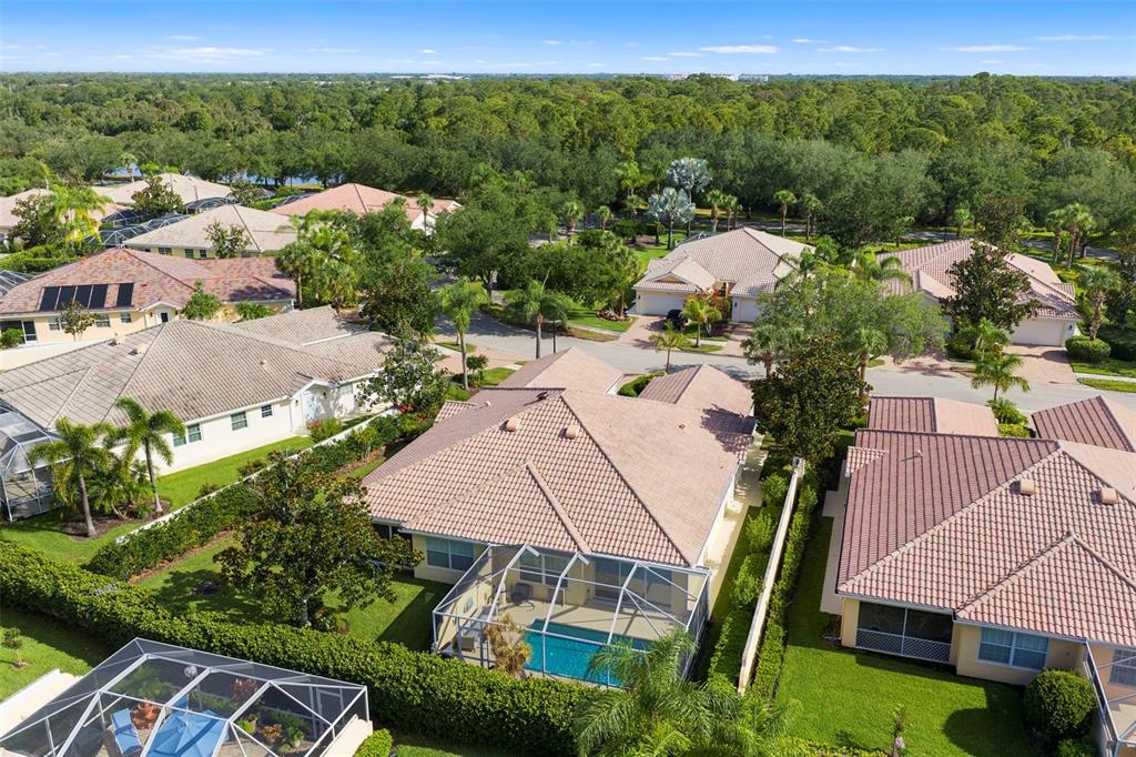 An aerial view shows several suburban houses with tiled roofs, screened-in pools, and lush landscaping — 5793 ITHACA WAY, SARASOTA, FL