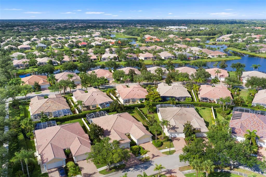 An aerial view shows a dense suburban neighborhood with many houses featuring tiled roofs — 5793 ITHACA WAY, SARASOTA, FL