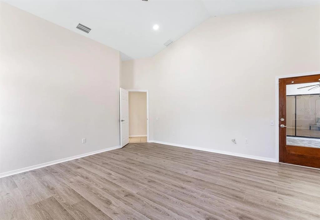 An empty room with vaulted ceilings, light-colored walls, and wood-look flooring — 1302 83RD STREET NW, BRADENTON, FL
