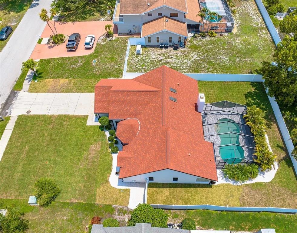 An aerial view shows a house with a red roof, a screened-in pool, and driveway — 1302 83RD STREET NW, BRADENTON, FL