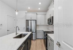 A modern kitchen features white cabinetry, stainless steel appliances, and a central island with a sink — 4345 ROUSH AVENUE, ORLANDO, FL