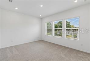 An empty bedroom with light gray carpet, white walls, and three windows — 4345 ROUSH AVENUE, ORLANDO, FL