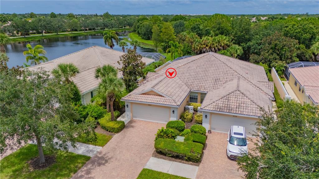 An aerial view shows a tan house with a tiled roof and a paved driveway — 8012 CAMMINARE DRIVE, SARASOTA, FL