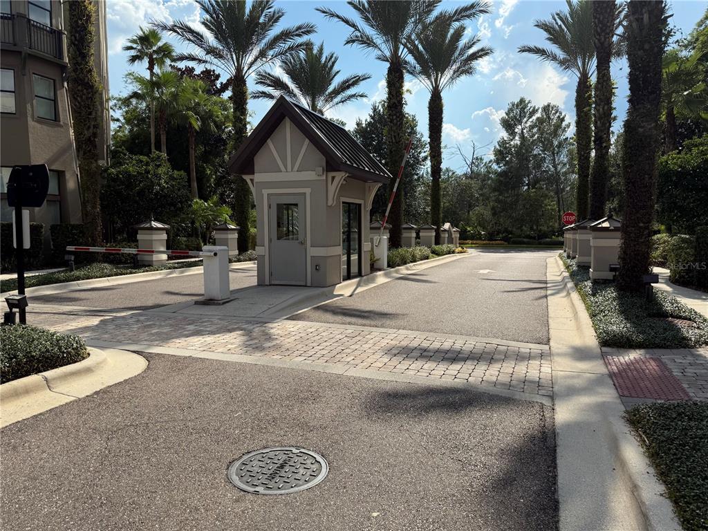 A gated entrance features a small guardhouse, palm trees, and a paved driveway — 14501 GROVE RESORT AVENUE UNIT 3712, WINTER GARDEN, FL