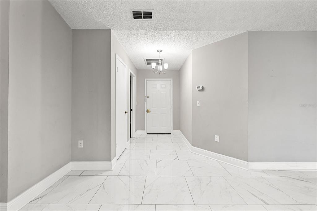An entryway with white marble-look tile flooring, gray walls, and a white front door — 3878 FEATHER DRIVE, LAKELAND, FL