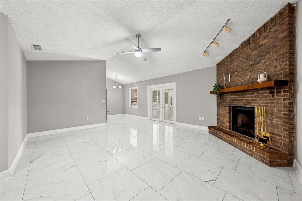 A living room features a brick fireplace, a leather sofa, two armchairs, and tile flooring — 3878 FEATHER DRIVE, LAKELAND, FL