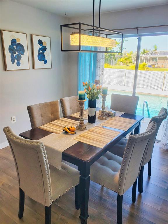 A dining room features a dark wood table, upholstered chairs, and a view of a pool — 4 GOLFVIEW ROAD, ROTONDA WEST, FL