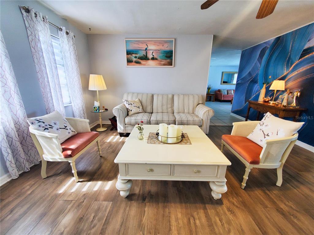 A living room features a striped sofa, two chairs with orange cushions, and a coffee table — 4 GOLFVIEW ROAD, ROTONDA WEST, FL